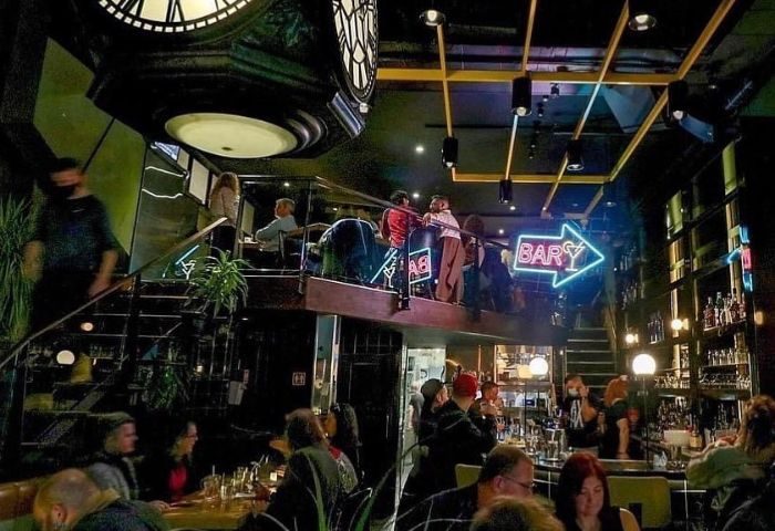 Le Saloon Gay Bar in Montreal: Interior view of the popular gay bar with patrons, neon bar sign, and multilevel seating areas.