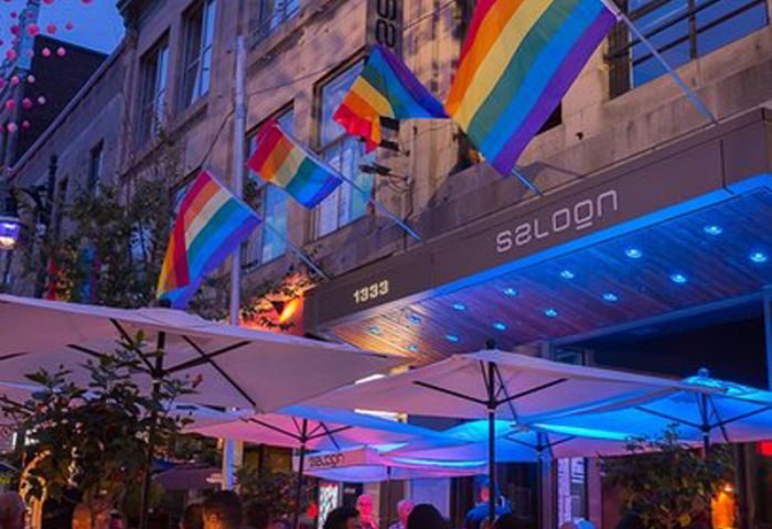 Le Saloon Gay Bar in Montreal. Rainbow flags adorn the entrance, with outdoor seating under umbrellas. Nightlife in Montreal's Gay Village.