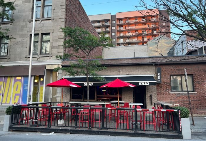 Le Stud gay bar in Montreal, Canada. Outdoor seating area with red chairs and umbrellas. A popular gay travel destination.