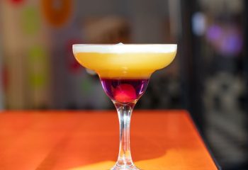 Colorful cocktail in Milan, Italy. Layered drink with cherry, perfect for gay travel adventures. LeccoMilano nightlife.