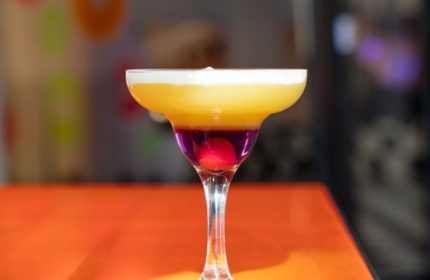 Colorful cocktail in Milan, Italy. Layered drink with cherry, perfect for gay travel adventures. LeccoMilano nightlife.