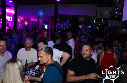 Lights Bar, a gay bar in Torremolinos. A crowded scene with men enjoying drinks and socializing in a vibrant, purple-lit atmosphere.