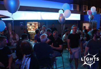 Lights Bar, a gay bar in Torremolinos. Crowded interior with men socializing, balloons, and a well-stocked bar. Gay travel advice.