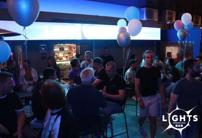 Lights Bar, a gay bar in Torremolinos. Crowded interior with men socializing, balloons, and a well-stocked bar. Gay travel advice.