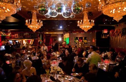 Lips Drag Queen Show Palace in New York. Interior view of the restaurant, chandeliers and disco balls hanging from the ceiling, people dining.
