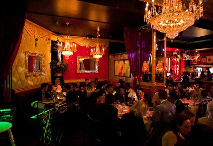 Lips Drag Queen Show Palace interior in New York. Patrons dine under chandeliers in the ornate, red-and-gold themed restaurant.