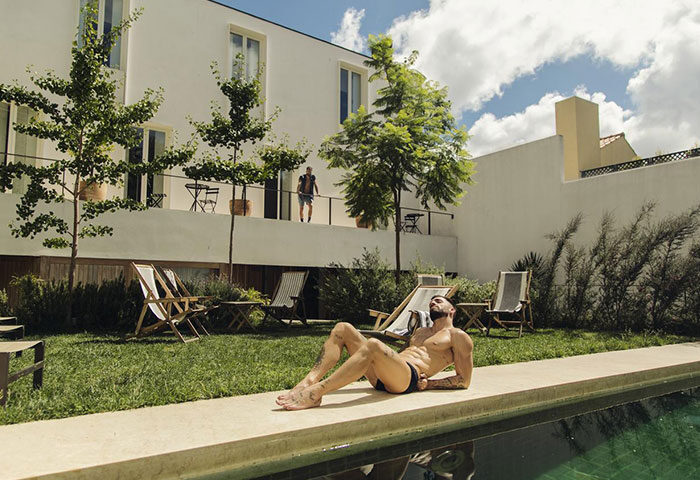The Late Birds Lisbon Gay Urban Resort pool scene. Man sunbathing by the pool at this best gay men-only hotel in Lisbon, Portugal.
