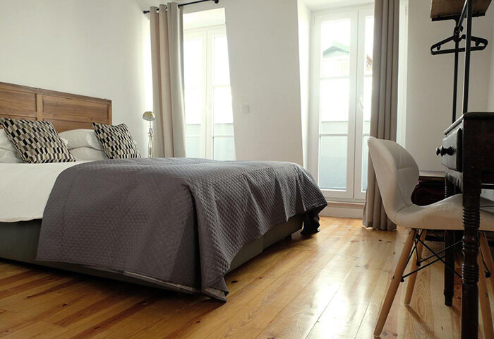 Lisbon Poets Inn Hostel room. Interior of a gay-friendly hotel in Lisbon's gayborhood. Features a double bed, desk, and bright windows.