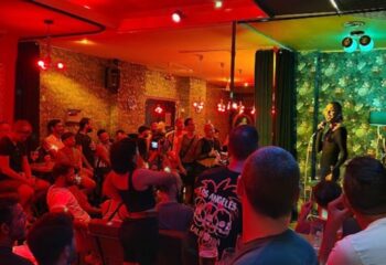 Lo de Carmen Gay Bar in Barcelona: A drag queen performs in a Barcelona gay bar with a crowd of gay men watching. Gay travel advice.