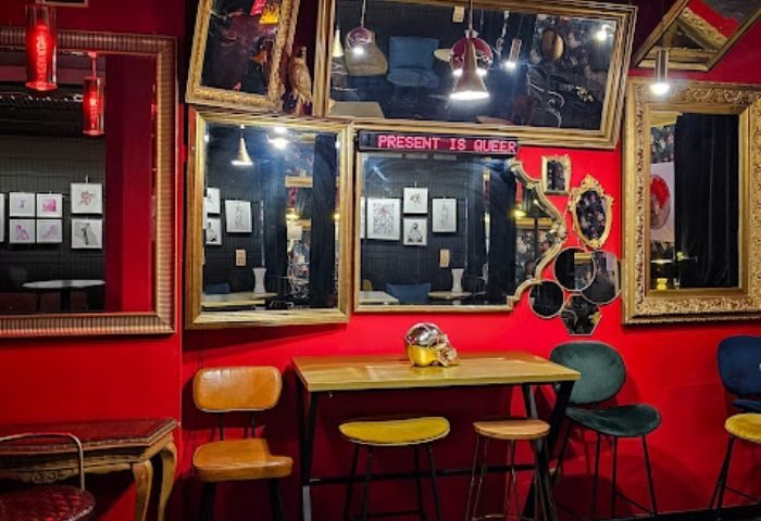 Lo de Carmen Gay Bar in Barcelona: Red walls, mirrors, and eclectic decor create a unique ambiance. Present is Queer sign.