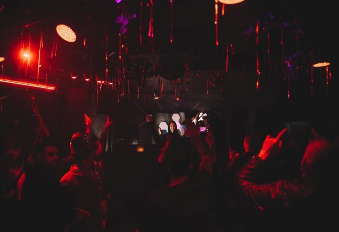 Lola's Club Ibiza gay club scene. Red lights illuminate dancing crowd. Gay nightlife in Ibiza, perfect for gay men travel advice.