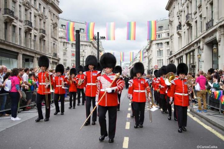 London Pride parade: marching band in red uniforms with rainbow flags overhead. Gay travel in London. London-Pride.jpg