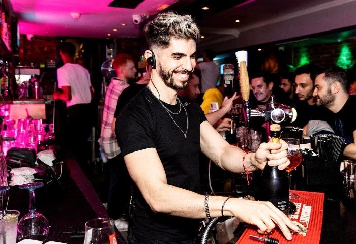 Bartender opening champagne at CIRCA Soho, London's trendiest gay bar on TikTok. A popular gay travel destination. Nightlife scene.