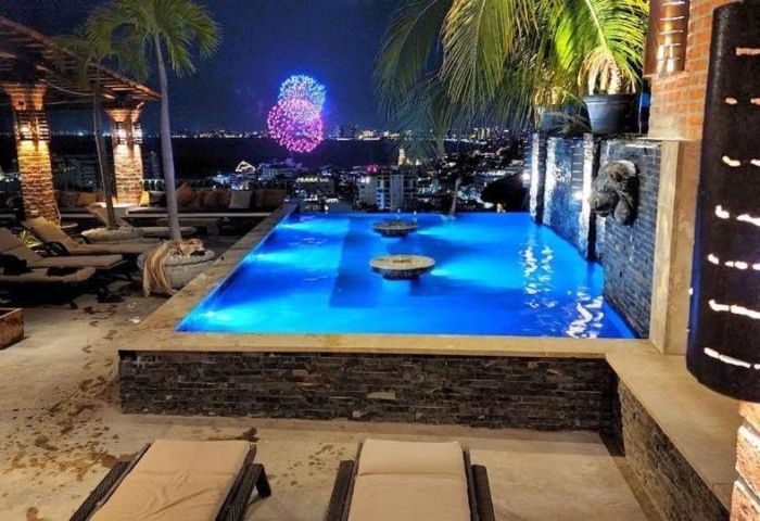 Night view of The Lookout Gay Bar in Puerto Vallarta. Infinity pool, city lights, and fireworks. Gay travel destination.