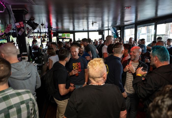 Crowded Lookout Gay Bar in San Francisco. Many gay men are standing, talking, and drinking. A popular destination for gay travel.