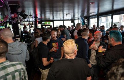 Crowded Lookout Gay Bar in San Francisco. Many gay men are standing, talking, and drinking. A popular destination for gay travel.