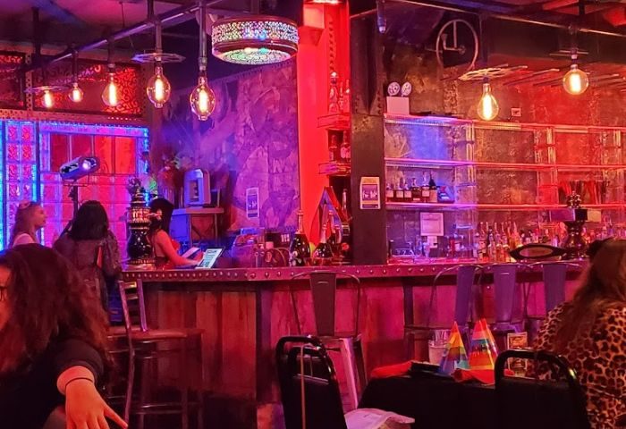 Lucky Cheng's Drag Cabaret, New York. Interior view of the bar area with red and purple lighting, tables, and patrons. Gay travel.