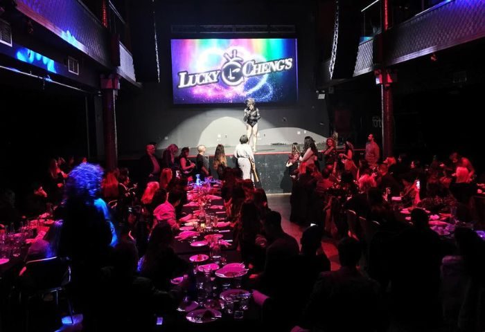 Lucky Cheng's Drag Cabaret in New York. Drag queen performs on stage. Audience sits at tables. Gay travel, nightlife, entertainment.