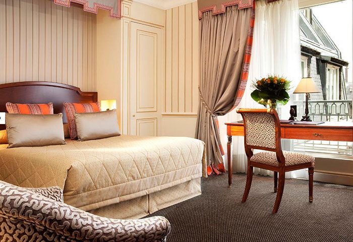 Hotel Napoleon, luxury gay hotel inspiration in Paris city center. Elegant room with bed, desk, chair, and view. Gay travel advice for discerning men.
