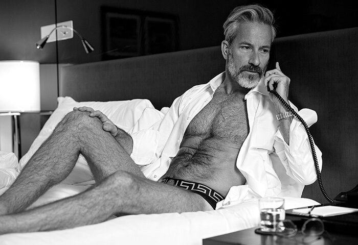 Gay man in Sofitel St James London Hotel. Luxury travel for gay travelers. Man on phone in hotel room. Instagram hotel. Black and white.