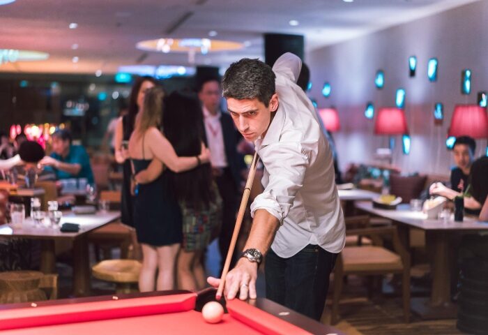 M Social Singapore: Man plays pool in stylish bar. Gay-friendly hotel offers nightlife and social scene for travelers.