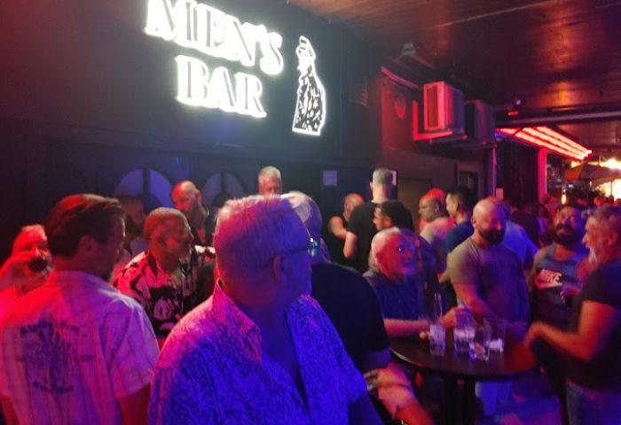Inside Men's Bar, a gay cruise club in Torremolinos. Crowd of men, neon sign, and bar scene. Gay travel destination.