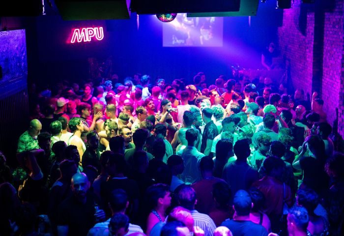 Le Belmont gay dance party in Montreal. Crowd of men dancing under neon lights. Gay nightlife travel advice. MPU club scene.