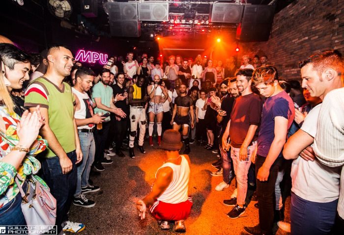 Montreal gay travel: Le Belmont's dance party. A diverse crowd of gay men watch a dancer in a circle at a lively MPU event.