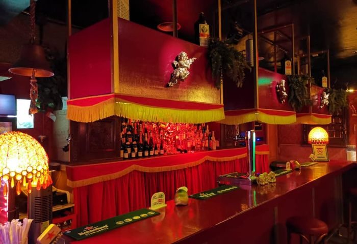 Interior of Macho Macho gay bar in Gran Canaria. Red decor, bottles, and ornate details create a unique ambiance for gay men travelers.
