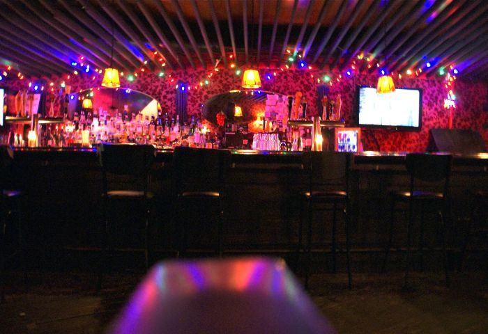 Interior of Macri Park, a gay video bar in New York City. Colorful lights adorn the bar area, creating a vibrant, fun atmosphere.