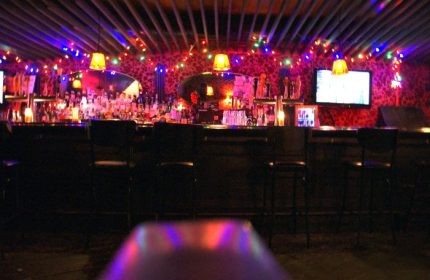 Interior of Macri Park, a gay video bar in New York City. Colorful lights adorn the bar area, creating a vibrant, fun atmosphere.