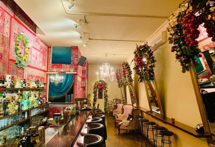 Interior of Madame George Lounge Bar, a gay bar in Barcelona. The walls are covered in carpets, & there's a chandelier.