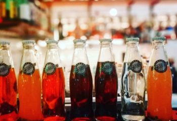 Magnebevo drinks at Pigneto, Rome. A row of glass bottles with colorful beverages. Gay travel in Rome, Italy. Popular local drinks.