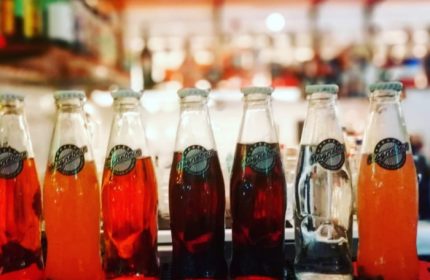 Magnebevo drinks at Pigneto, Rome. A row of glass bottles with colorful beverages. Gay travel in Rome, Italy. Popular local drinks.