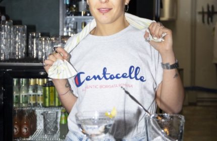 Malo Glitter Bar Rome: Bartender with Centocelle shirt, serving drinks. Gay travel advice for Rome's nightlife, bars, and gay-friendly spots.