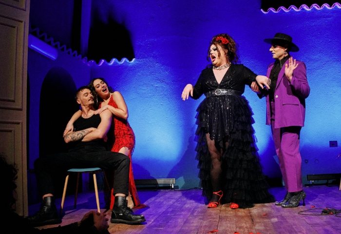 Malo Glitter Bar Rome stage performance. Drag queen in black dress and two actors in purple suit and red dress on stage. Gay nightlife.