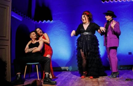 Malo Glitter Bar Rome stage performance. Drag queen in black dress and two actors in purple suit and red dress on stage. Gay nightlife.