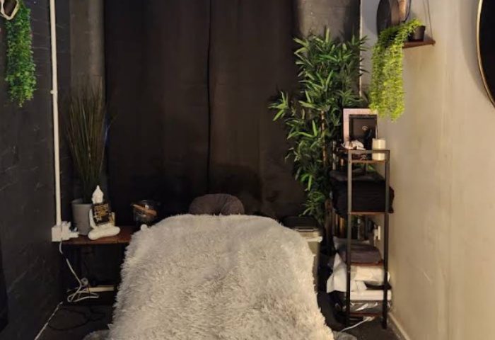 Manchester Queer Massage: Massage table with a soft, grey cover. Plants and decorations add a relaxing ambiance to this gay-friendly space.
