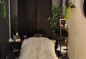 Manchester Queer Massage: Massage table with a soft, grey cover. Plants and decorations add a relaxing ambiance to this gay-friendly space.