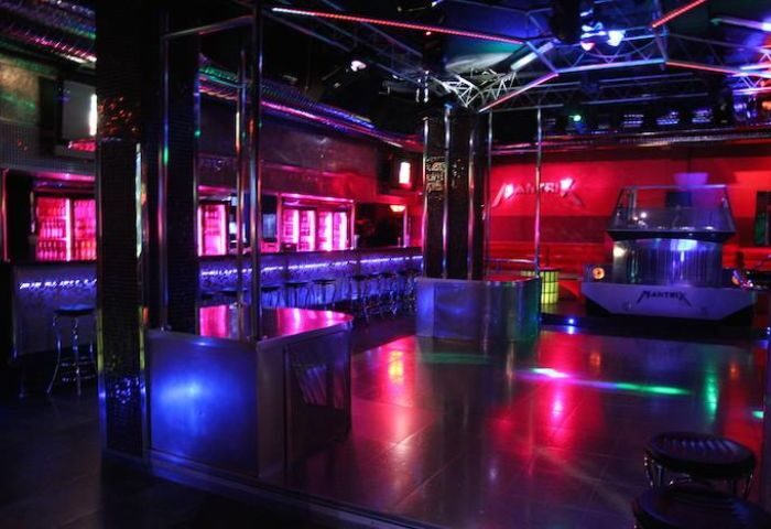 Interior of Mantrix Gay Club in Gran Canaria. Dance floor with bar, stage, and colorful lighting. Gay travel advice.