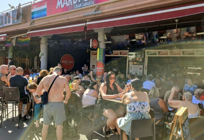 Mardi Gras gay bar in Gran Canaria. Outdoor seating area with people at tables. Gay travel destination for gay men.