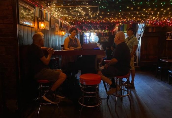 Marie's Crisis Sing-a-Long Bar in New York. Patrons at the bar, which is decorated with string lights. Gay travel destination.