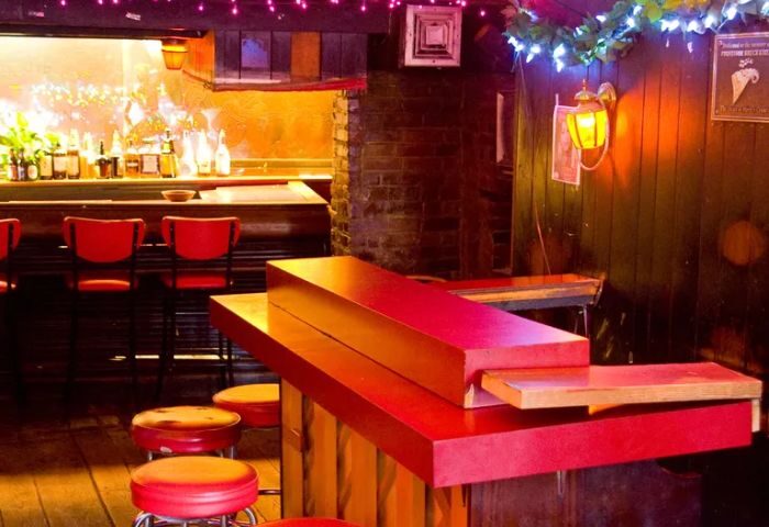 Marie's Crisis Sing-a-Long Bar in New York. Red stools line the bar. A piano sits ready for a singalong at this popular gay bar.