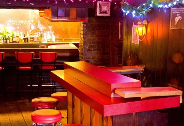 Marie's Crisis Sing-a-Long Bar in New York. Red stools line the bar. A piano sits ready for a singalong at this popular gay bar.