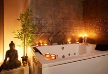 Barcelona gay massage: Spa bathroom with jacuzzi, candles, and Buddha statue. Relaxing ambiance for a gay travel experience.