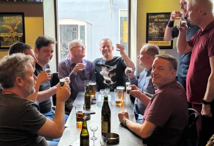 Gay men at Masken Bar in Copenhagen. Group of friends drinking beer and shots in a pub. Gay travel advice.