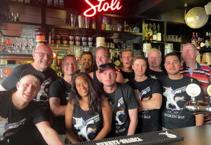 Masken Bar Copenhagen staff photo. Gay bar in Copenhagen, Denmark. Group of people wearing Copenhagen Pride shirts behind the bar.