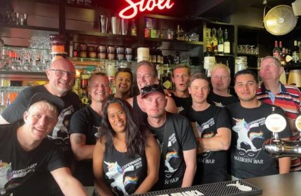 Masken Bar Copenhagen staff photo. Gay bar in Copenhagen, Denmark. Group of people wearing Copenhagen Pride shirts behind the bar.