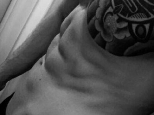 Black and white close-up of a torso with a tattoo. Massage By Bret, a gay massage spa, offers relaxation and bodywork for gay men.