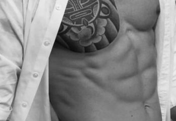 Torso of a fit man with tattoo, shirt open. Massage By Bret, gay massage spa. Male physique, black and white. Gay travel advice.